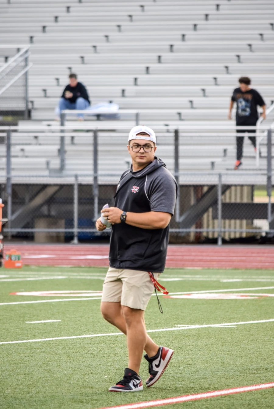 Coach Bartlett walking on the football field during a coaching session.
